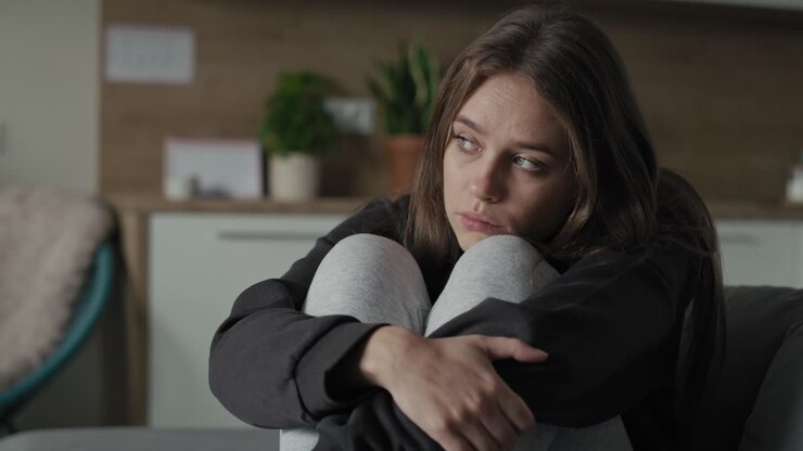 Caucasian sad woman sitting at the sofa with depression.