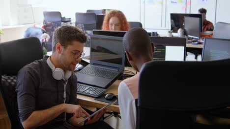 vista lateral de un joven equipo de negocios de raza mixta planeando y sentado en un escritorio en una oficina moderna 4k