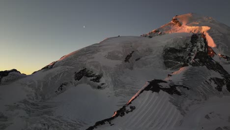 aerial view of a snow-covered summit during a sunrise, orange and blue sky