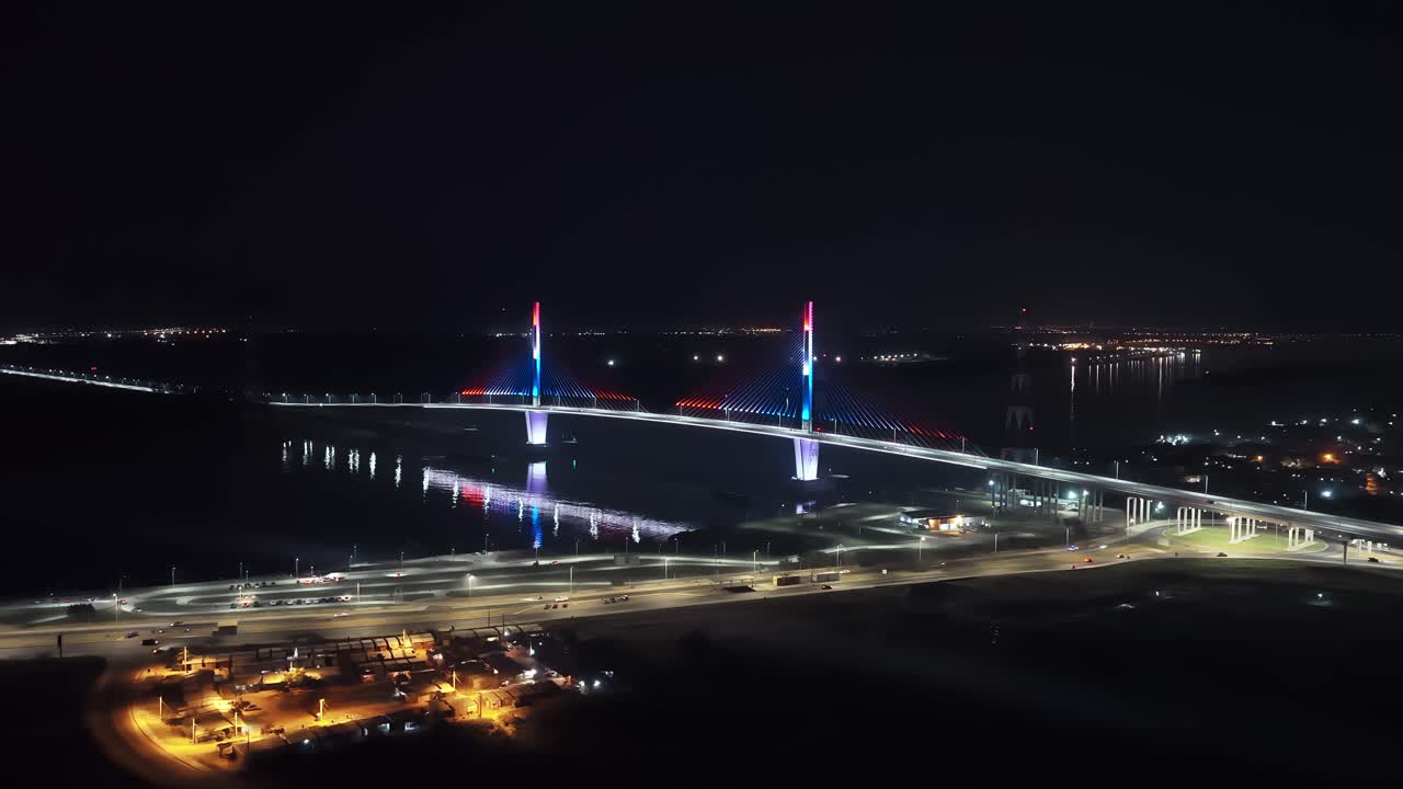 Panoramic nighttime aerial of illuminated Heroes of Chaco Bridge over Paraguay River in Asuncion