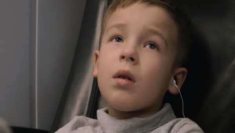 niño viendo la tv en el tren escuchando audio con auriculares