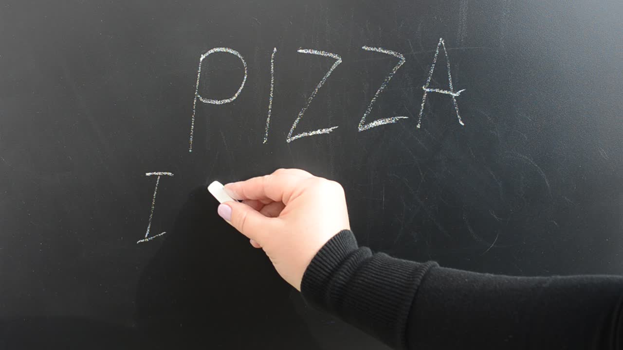 Scriviamo su una lavagna la pizza italiana. Scritta a gesso su una lavagna.