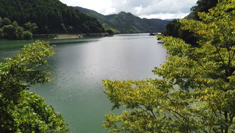 Scenic-lake-valley-with-mountains-in-Asago-Hyogo-Japan,-tilt-view-of-serene-cloudy-summer-day