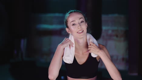 Portrait-Of-Attractive-Young-Female-Athlete-With-Towel-Taking-Break-After-Exercising-In-Gym