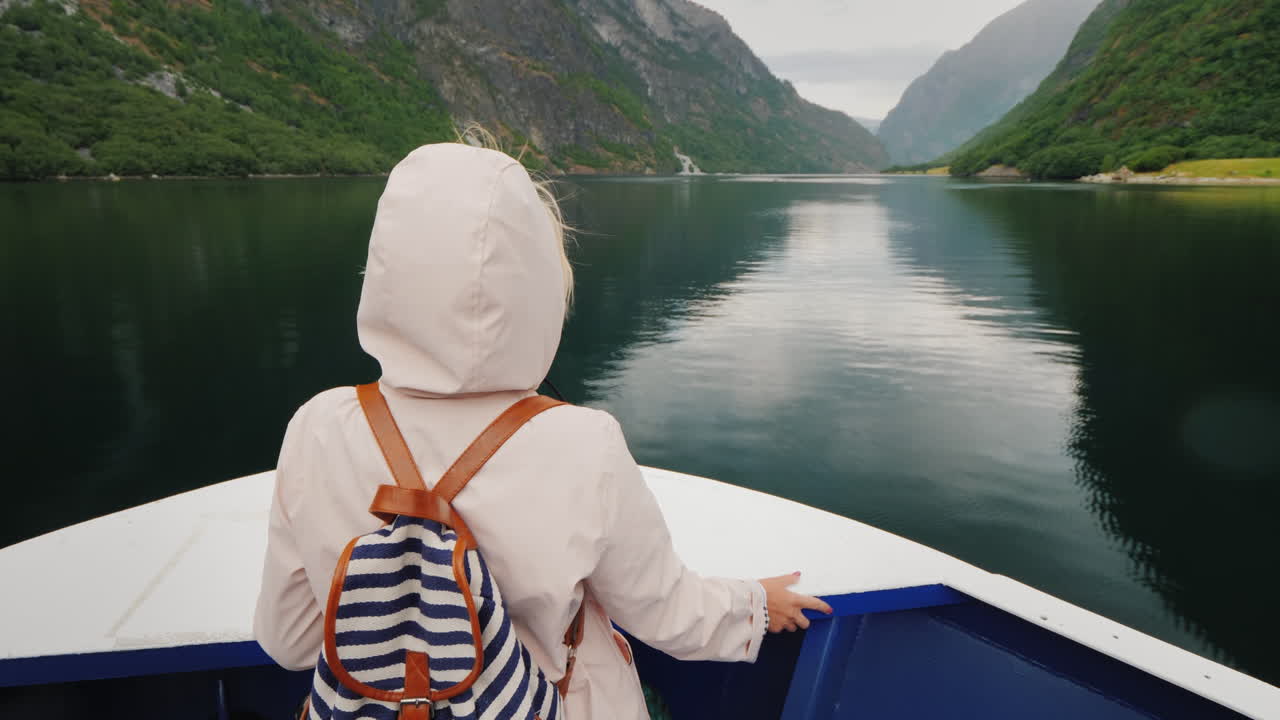 한 여성이 노르웨이 피요르드에서 쌍안경 순항을 통해 바라보는 배의 뱃머리에 서 있다
