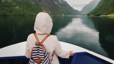 a woman is standing on the bow of the ship looking through binoculars cruise on the fjords of norway