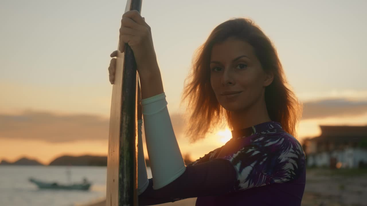 Woman with surfboard at sunset on the beach