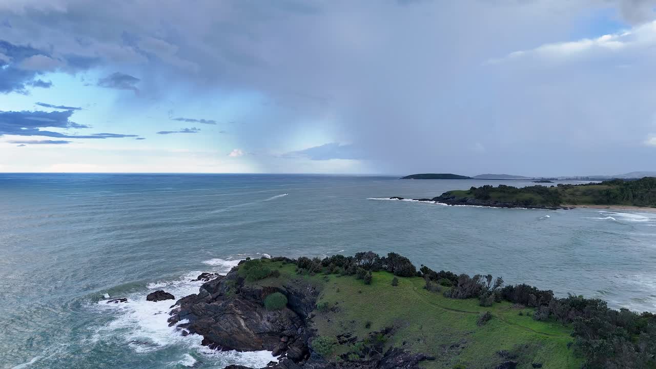 Aerial footage captures rugged cliffs and expansive ocean under dynamic skies at Charlesworth Bay, Coffs Harbour, Australia