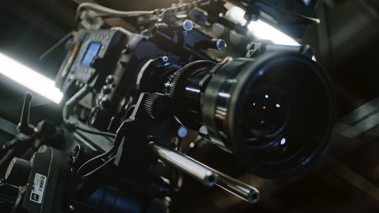 프로페셔널 영화 카메라와 긴 텔레포토  ⁇  렌즈의 낮은 각도 촬영, 원격 장치가 기어를 돌리고 렌즈 요소가 초점 거리를 변경하기 위해 움직이고 있습니다