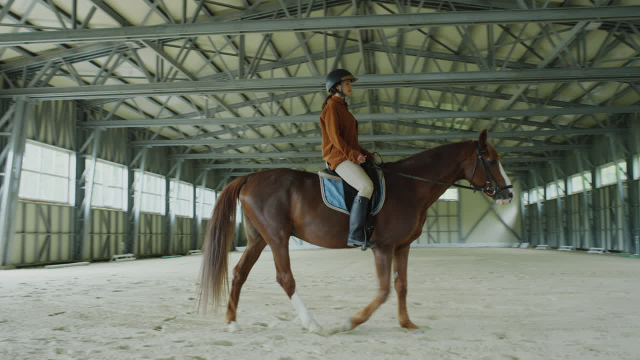 Woman Riding a Horse in an Indoor Equestrian Arena