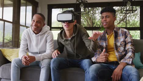 happy diverse male teenage friends playing video games and using vr headset at home, slow motion