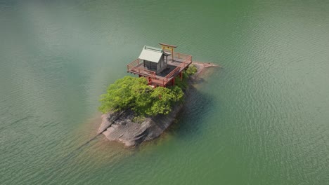 Luftdrohne-Fliegt-Allein-über-Dem-Tempel-Inmitten-Der-Wasserlandschaft-Von-Kyoto,-Japan,-Religiöser-Orangefarbener-Shinto-Eingang-Mit-Tori-Türen-Und-Holzarchitektur-Am-Blauen-See