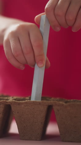 little girl makes holes in soil in seedling tray cells at home closeup slow motion. planting seeds for garden. teaching child to take care of plants
