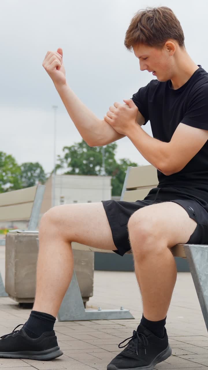 Person experiences arm cramp outdoors, expressing discomfort, casual setting