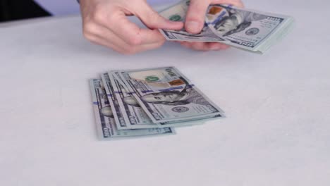 bank teller counting new one hundred dollar bills on white table