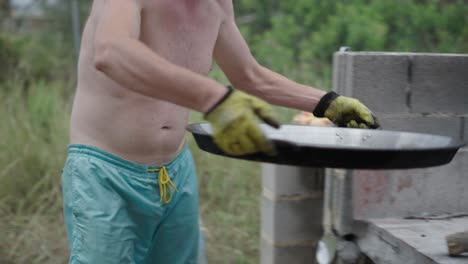 a person prepares a large paella pan with oil for outdoor cooking