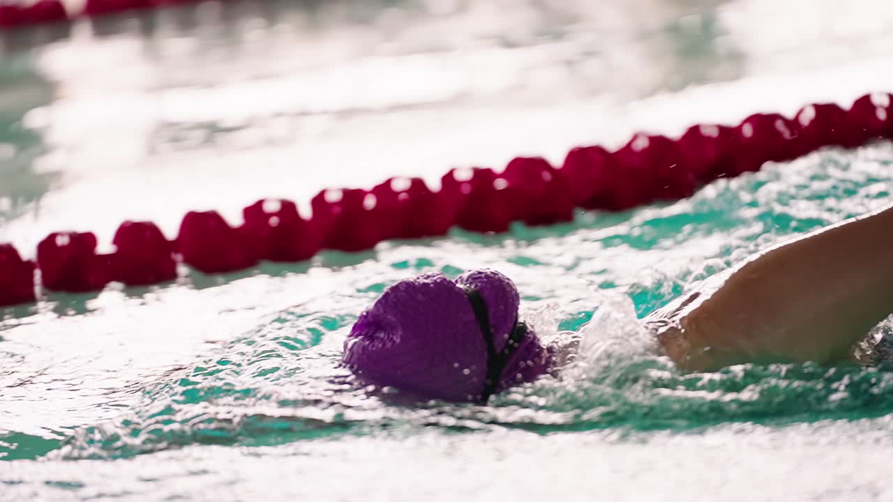 Gros plan d'un nageur en entraînement dans une piscine intérieure.