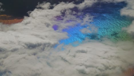 rainbow colors on planet surface from above with white clouds in the atlantic ocean while travelling in plane for holidays