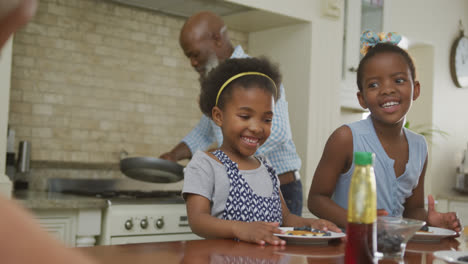 Happy-african-american-grandparents-with-granddaughters-having-breakfast-and-talking