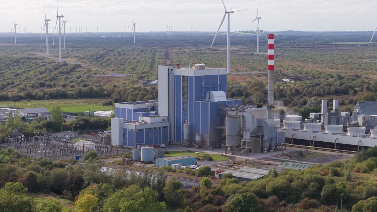Biomass power station in scenic Irish landscape with wind turbines