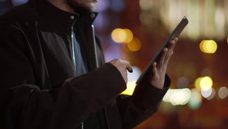 las manos del tipo navegando por internet en la tableta al aire libre. las manos del hombre usando la tableta en la calle.