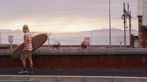 caucasian male surfer holding a wooden surfboard and walking