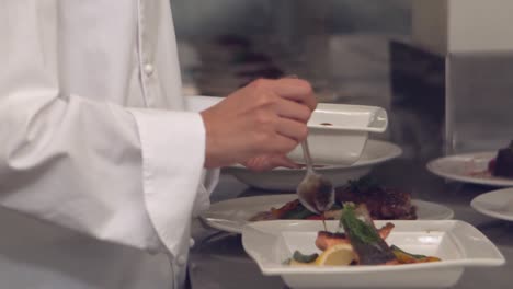 chef pouring sauce over fish dish