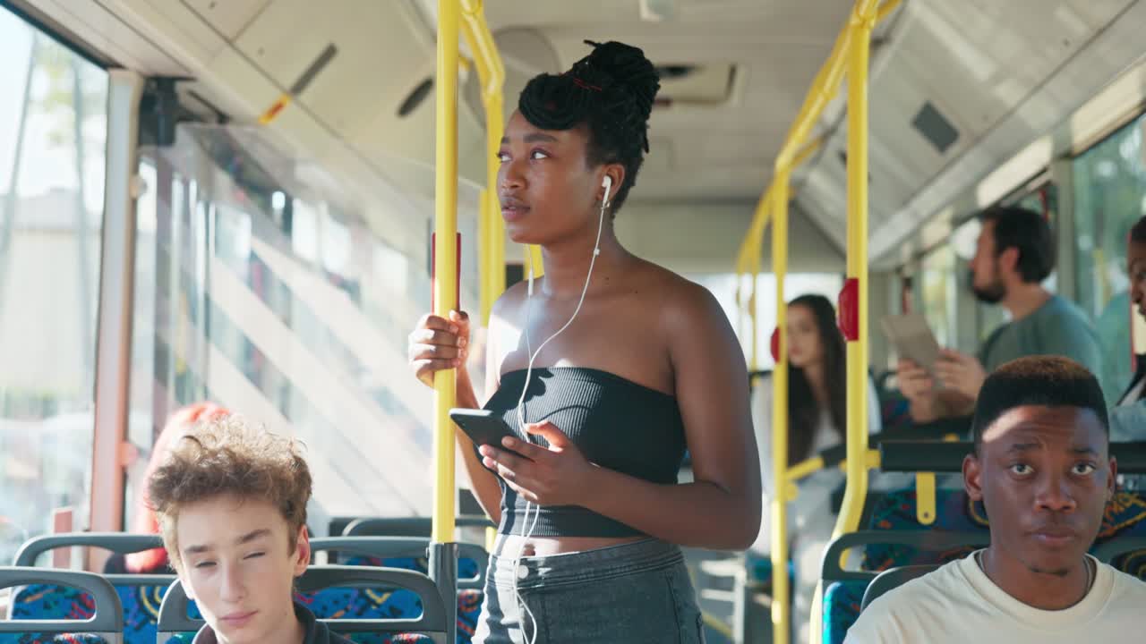 좋은 기분의 웃는 여자가 아침에 학교로 버스를 타고, 귀에 헤드폰을 걸고, 듣고