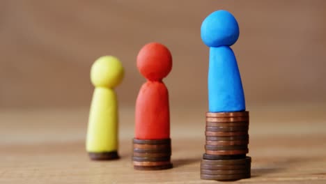 grupo de figuras rojas, azules y amarillas de pie en pilas de monedas