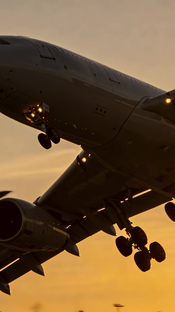 Vídeo vertical: Avião de passageiros em descida iniciando a aproximação final para a pista ao pôr do sol, com trem de pouso