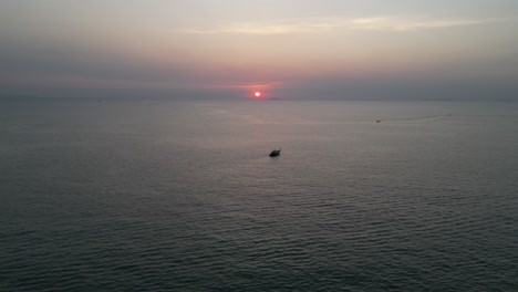 barco tradicional de cola larga navegando hacia la puesta de sol sobre el golfo de tailandia cerca de pattaya