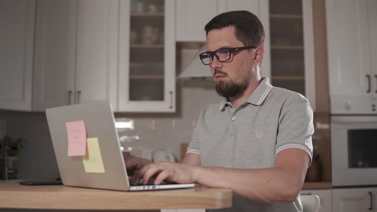 hombre trabajando en una computadora portátil en la cocina