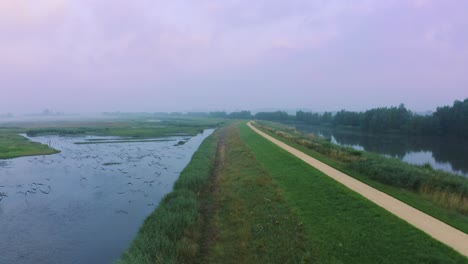 Flock-Of-Birds-Flying-Over-Arkemheen-Polder-With-Narrow-Road-In-Nijkerk,-Netherlands