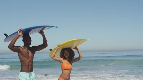 pareja afroamericana con tablas de surf en sus cabezas