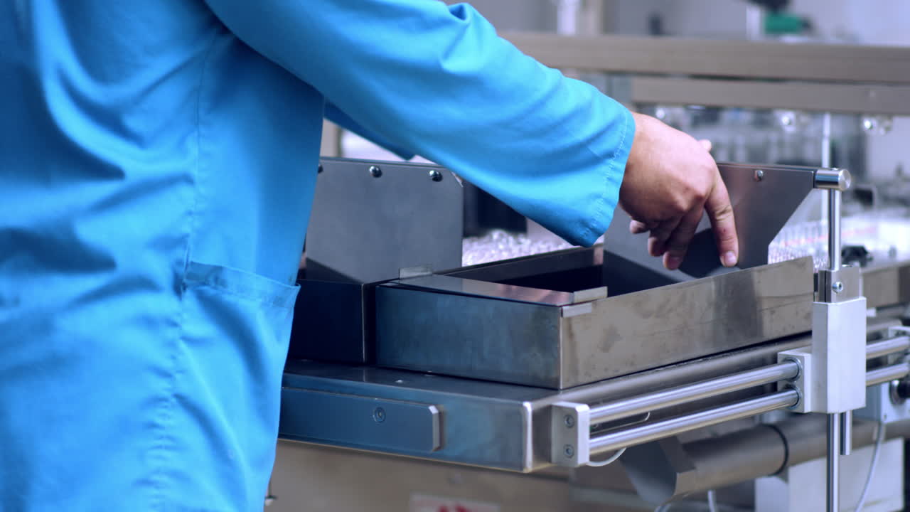 manos de trabajadores que trabajan con máquinas de envasado farmacéutico