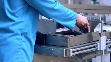 worker hands working with pharmaceutical packaging machine