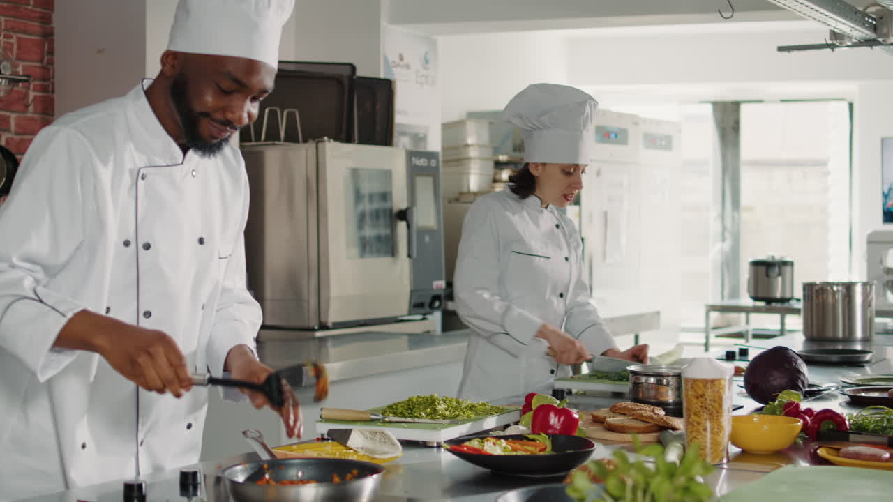 Male chef pouring cut vegetables on delicious dish in pan