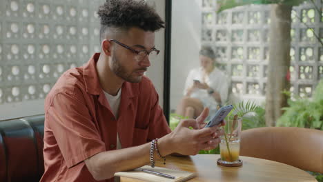 man taking notes in copybook at cafe table