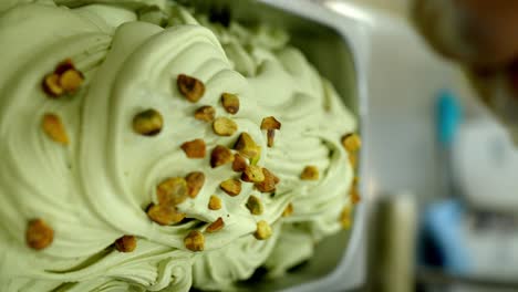 factory worker putting chunk of pistachio into a tray of pistachio ice cream