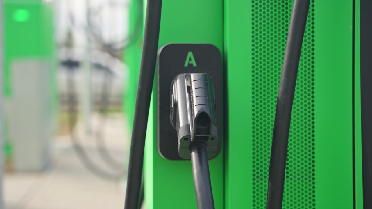 Electric car charger cable attached to green charging station