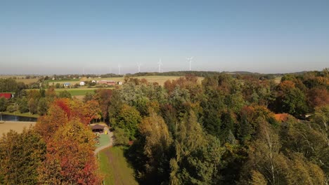 Evening-view-of-autumn-forest-and-wind-turbines-or-windmills-farm-field-in-the-background