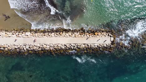 aerial top dowwn view of old ruined pier on the beach with tourists