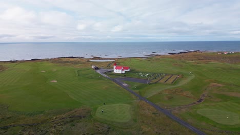 Escena-De-La-Vida-Cotidiana,-Golfistas-Jugando-En-El-Campo-De-Golf-Junto-A-La-Típica-Iglesia-Pintoresca,-Islandia