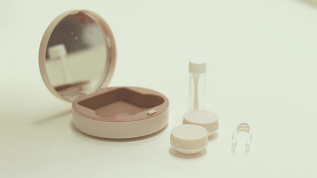 Close up to hands arranging the content of a contact lens container