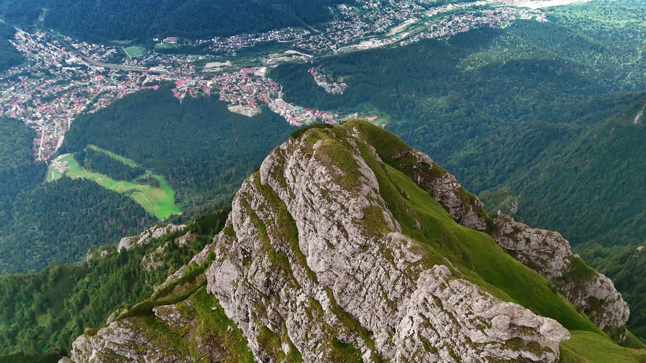 Majestic view of Bucegi Mountains over Busteni village. Stunning panoramic view from the summit of Bucegi Mountains, overlooking Busteni village and lush green valleys below