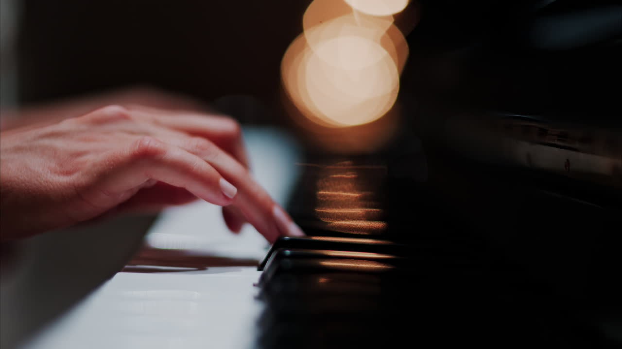 Close up of a woman's hands playing the piano with blurry lights on the background