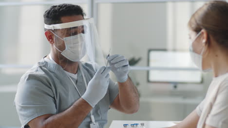 médico en uniforme de protección dando la vacuna a una paciente