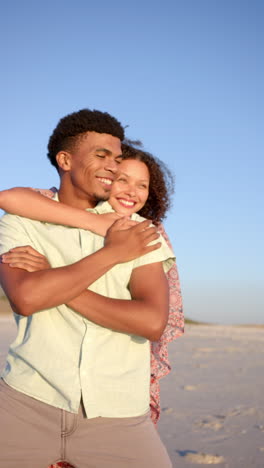 vertical video: embracing on beach, couple smiling and enjoying sunset together