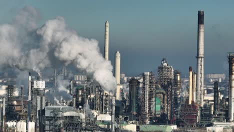 aerial drone shot of petrol refinery bellowing smoke