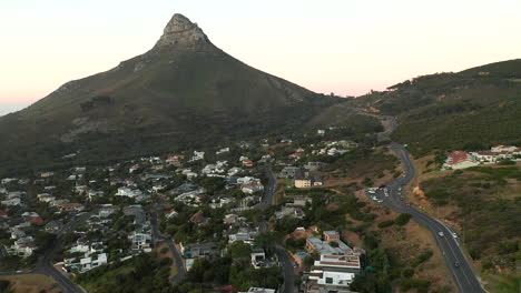 Vista-Aérea-De-La-Carretera-Escénica-En-La-Bahía-De-Campamentos-Con-La-Montaña-De-Cabeza-De-León-En-Sudáfrica---Disparo-De-Drones